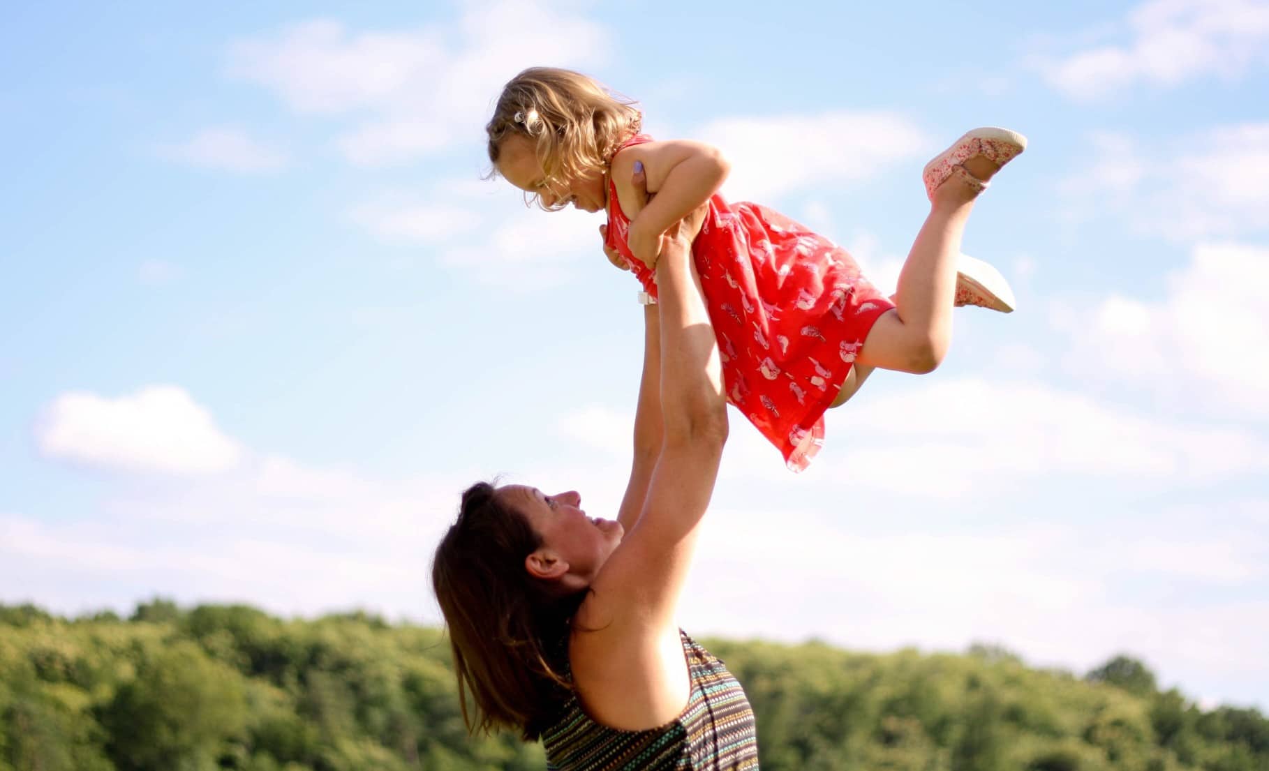 Happy mother holds her daughter up in the air