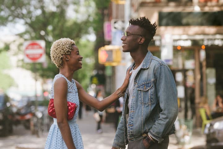 Young woman and man standing in the street in New York City, talking and flirting