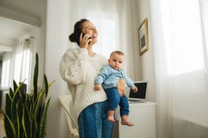 Freelance mother talking on phone with baby in arms.