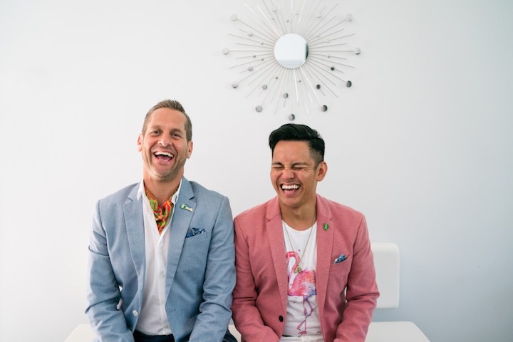 a gay couple sit together, laughing