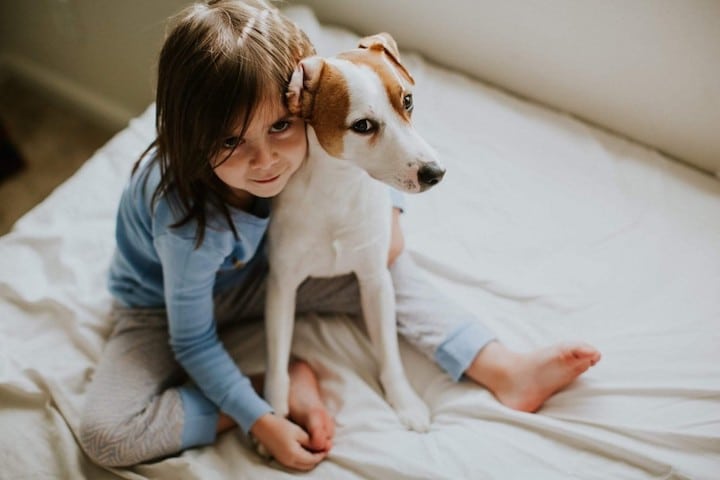 A little girl snuggles with her dog