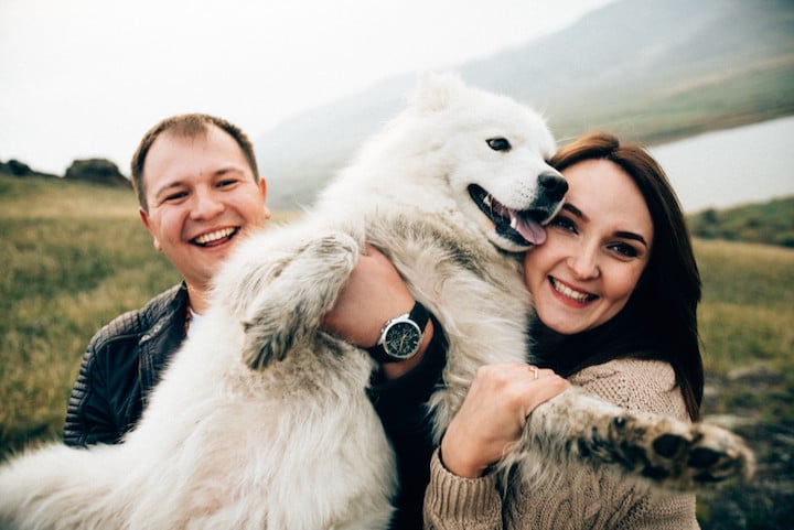 A couple plays with their dog as they enjoy the outdoors.