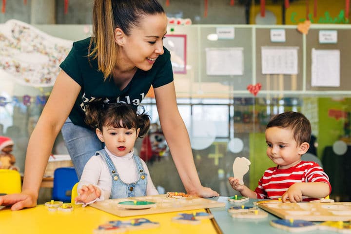 A young daycare worker plays with two happy children