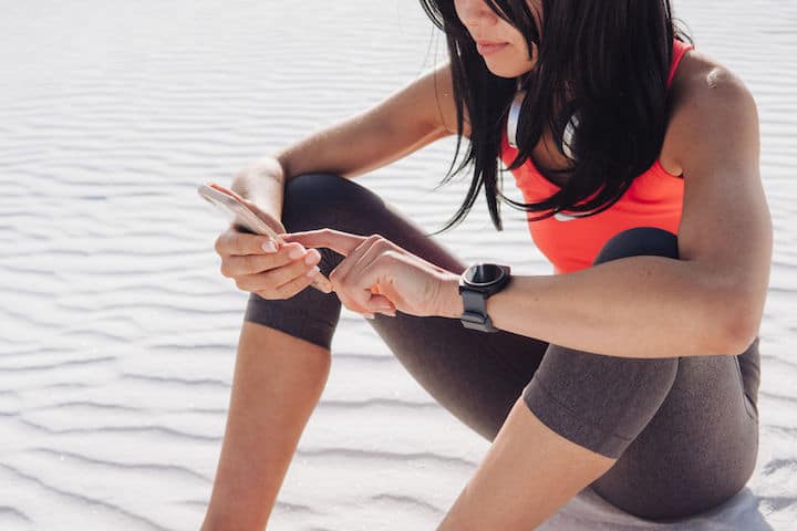 Fit young woman checks her iphone after a run