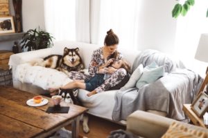 Mom cuddles on couch with two dogs and kid