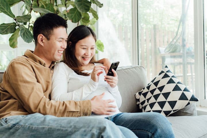 A pregnant couple uses their phone to get a quote on life insurance