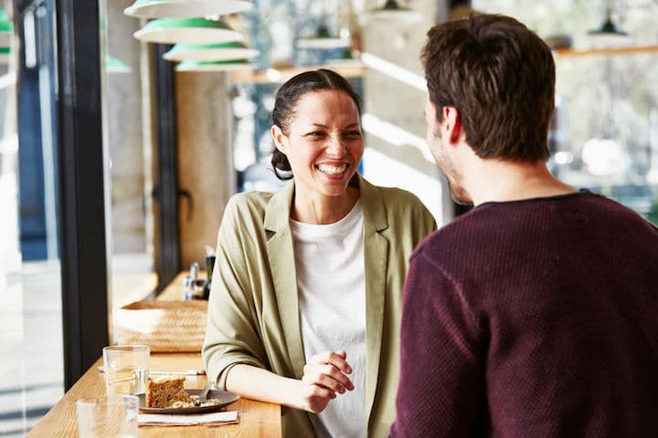 Smiling mid adult businesswoman with male colleague in restaurant