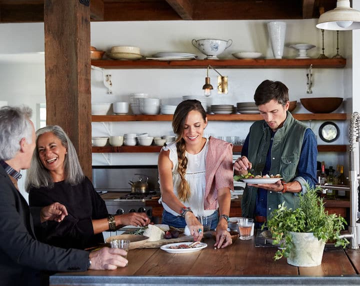 Family and friends have fun cooking together in a rustic, wood-based kitchen