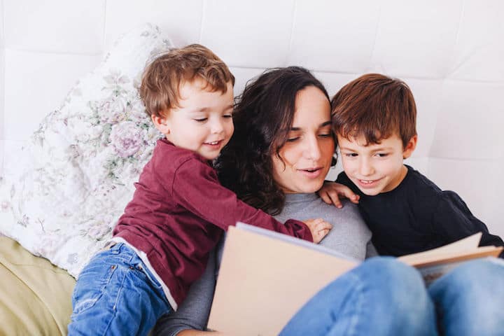 Mother reads to her two sons, a little boy and a toddler