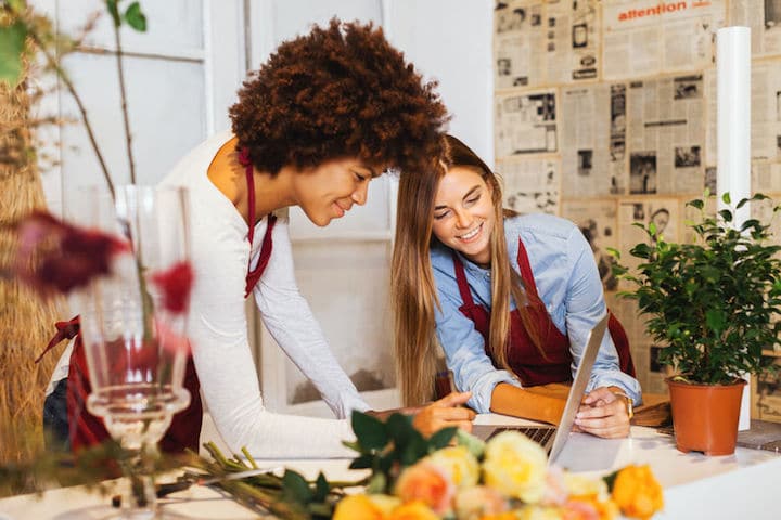 Two female florists type on a laptop at work