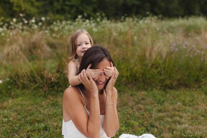 A little girl playfully covers her mothers eyes