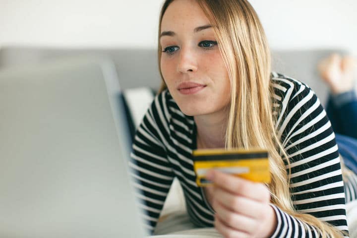Woman shops online with her laptop, paying via credit card