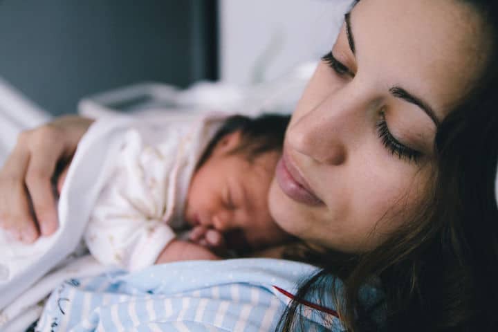 Mother dozes off while holding her newborn infant to her chest