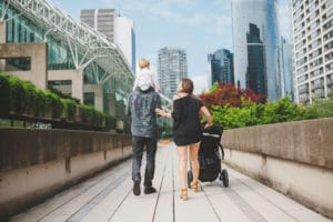 Parents walk their toddlers on a boulevard in a big city