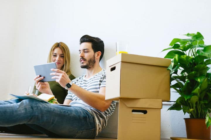 Young couple takes a break from unpacking in their new home to look up something on their tablet