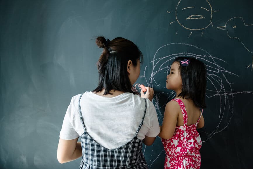 Mom teaching her daughter on a chalkboard