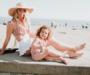 Mom with big sunhat (Jaime McFaden) sits on the beach with her cute toddler