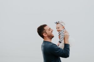 Dad smiles at his baby as he holds her up
