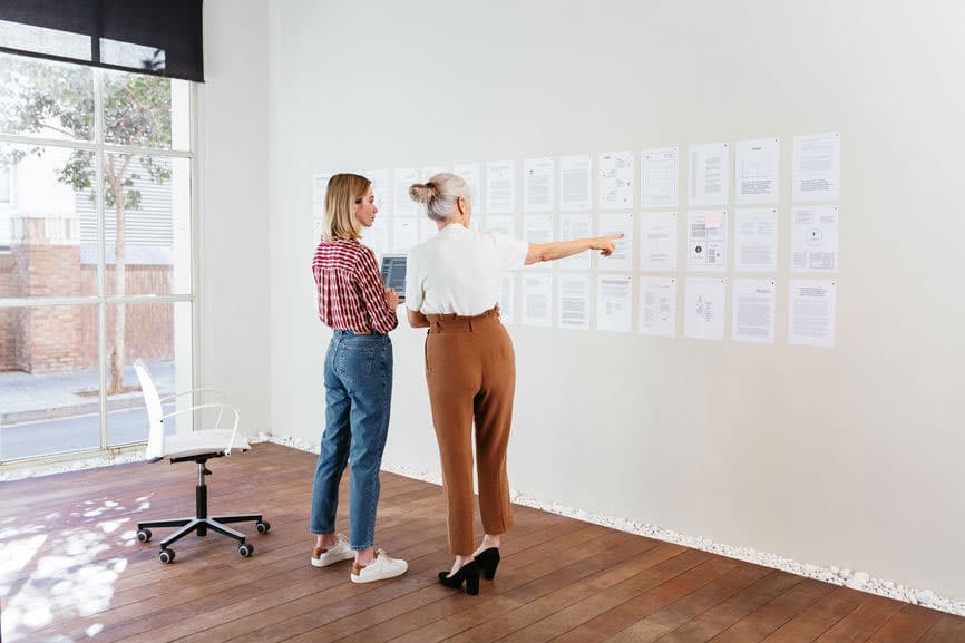 Two women collaborating on a white board