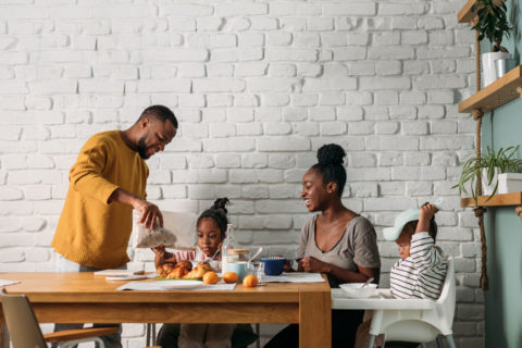 A family eats breakfast at a kitchen table together