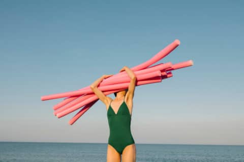 a woman on the beach holding a noodle