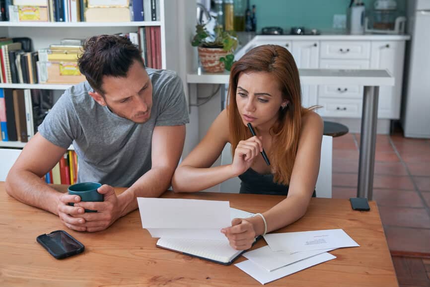 young couple calculating juggling their finances, managing debt overdue credit card bills mortgage stress troubled