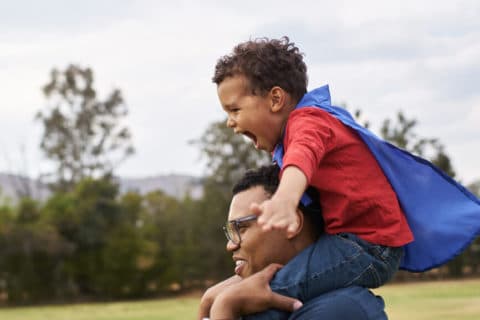 Black Family in the park, playing with kid. Dad is having happy son on shoulders, child playing with parent. Concept of family happiness