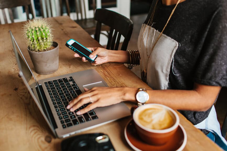 Femme au café prenant un brunch et travaillant sur son ordinateur portable et son téléphone portable.
