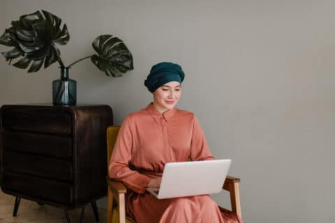 Smiling Muslim woman freelancer working on a laptop