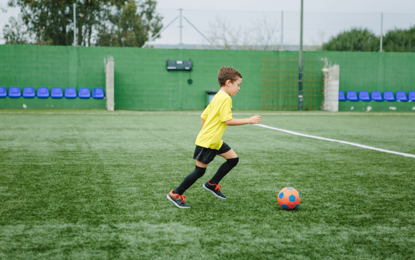 Little boy doing some football training and coaching on an astroturf pitch.