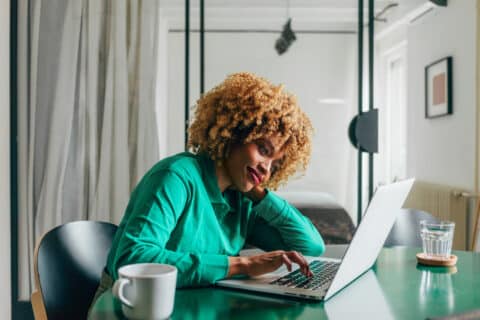 Close-up of beautiful casually dressed woman in her forties sitting at home and working on the computer
