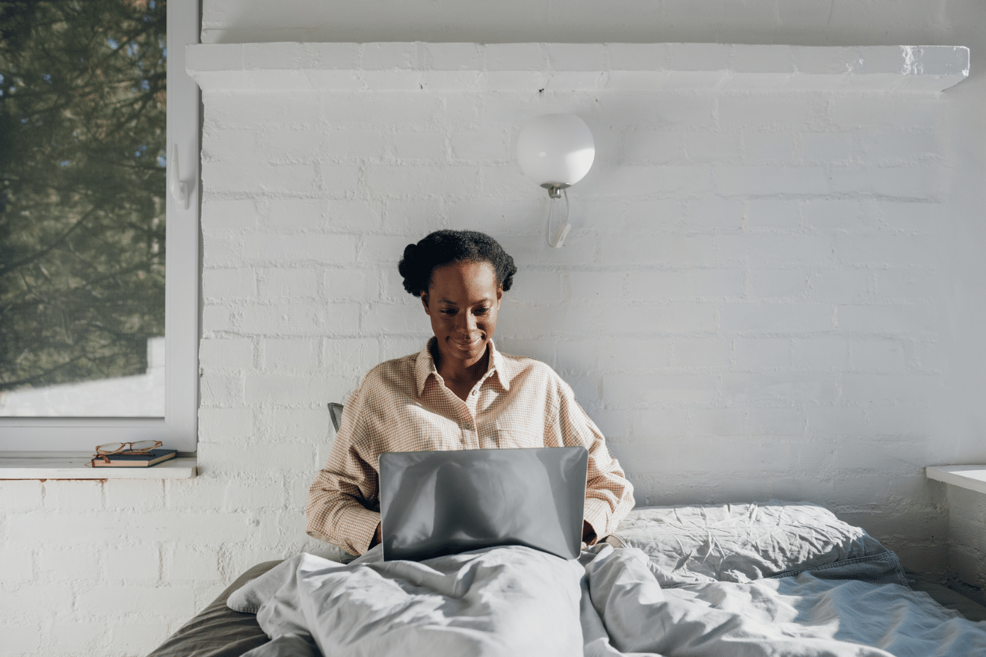 Portrait of beautiful black woman sitting in bed in bedroom and using her computer