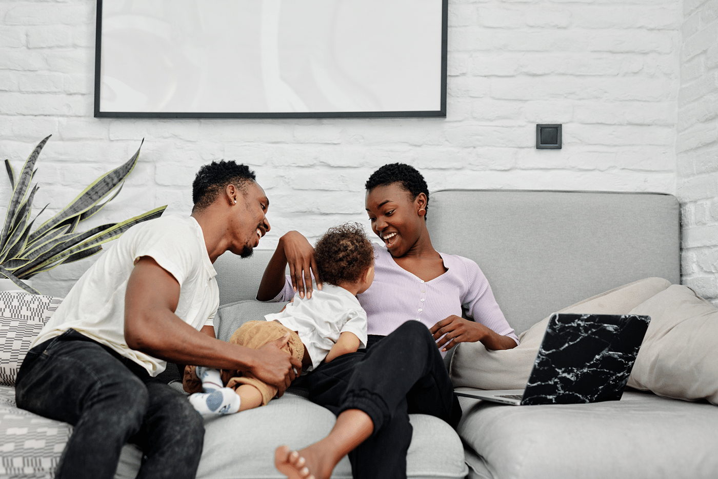 Side view of little boy, wearing in light t-shirt and pants, reclining on couch in living room, looking at mother and receiving attention from parent in living room