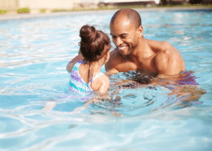 African American father teaching his young daughter how to swim in swimming pool at a resort in Calistoga, California.
