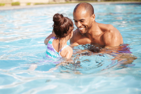 African American father teaching his young daughter how to swim in swimming pool at a resort in Calistoga, California.
