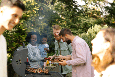 Group of friends having barbecue party outdoors, hanging out, drinking, grilling food, enjoying