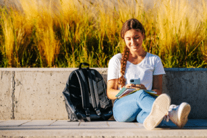 Portrait of a beautiful, young and intelligent-looking blonde braids college student woman wearing a white shirt and jeans smiling as she studies at the campus of her university