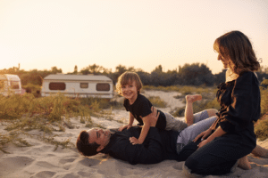 young family playing on the beach at sunset on a van background